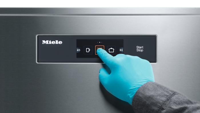 A hand with a blue glove is usin a touch screen control panel
