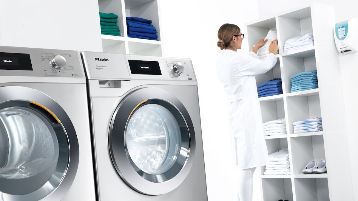 Máquinas de lavar roupa industriais e mulher com bata branca em pano de fundo