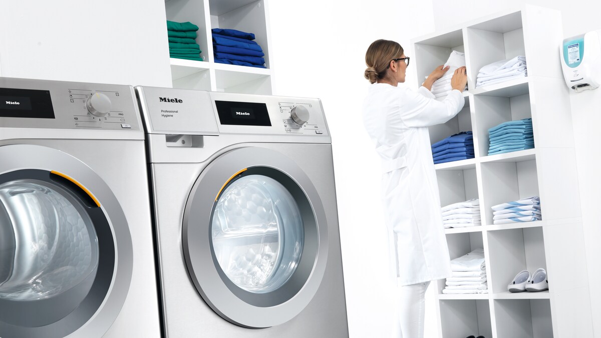 Industriewaschmaschinen und Frau mit weißen Kittel im Hintergrund
