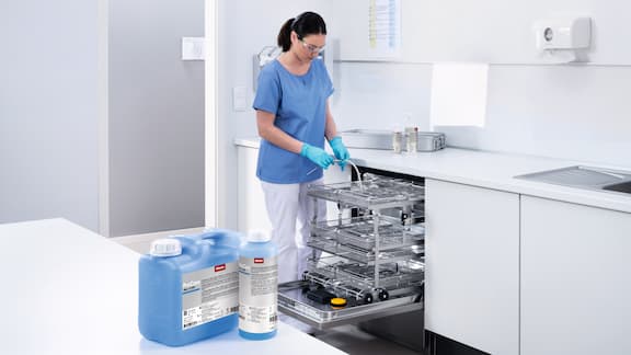 Lægeassistent fylder rengørings- og desinfektionsmaskinen.