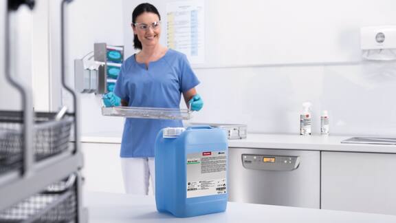 Odborná zdravotnická pracovnice uklízí ve sterilizační místnosti ordinace. V popředí stojí balení procesní chemie ProCare Med.