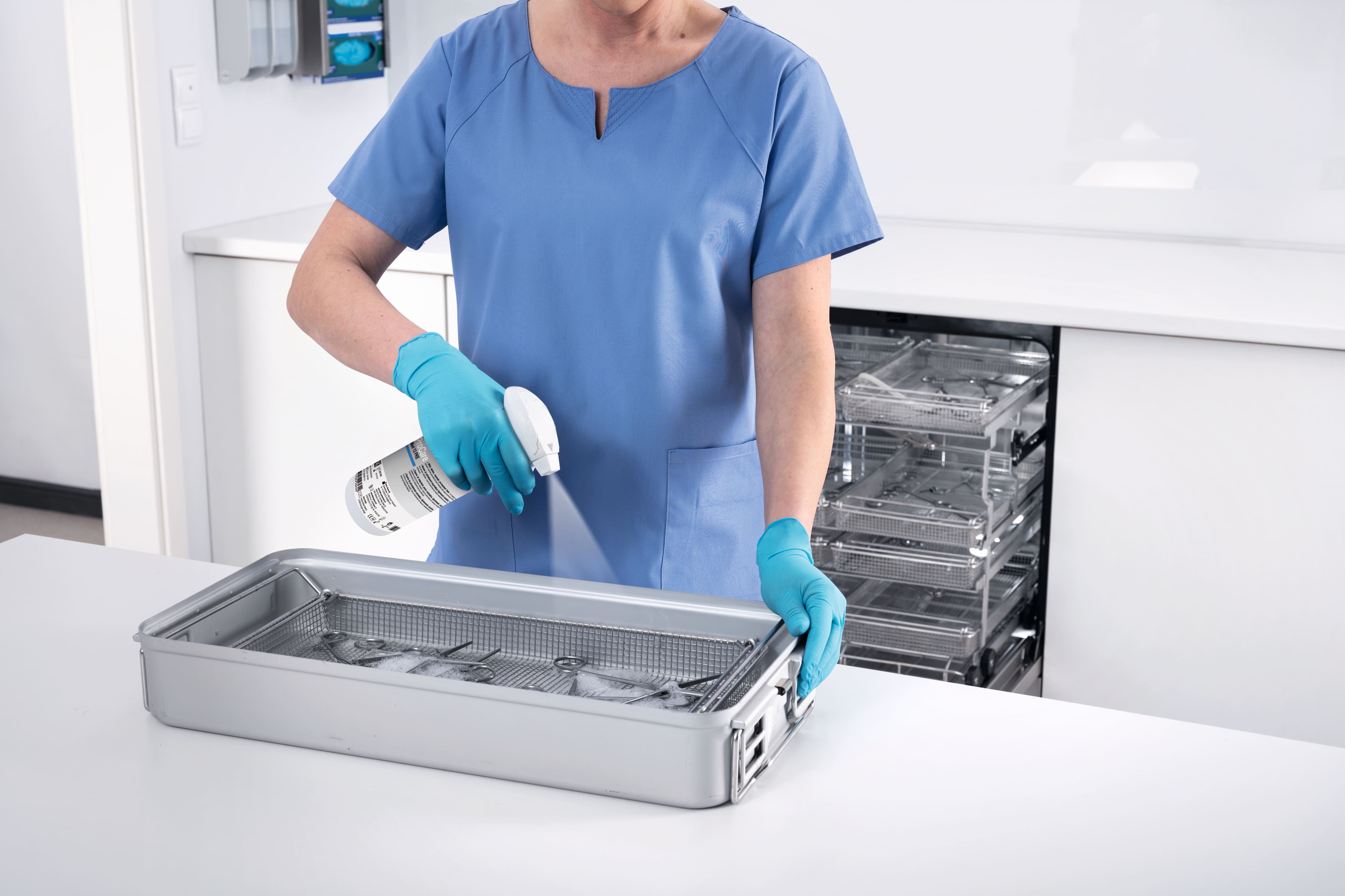 Mitarbeiter mit Schutzkleidung säubert Spülmaschineneinsatz.