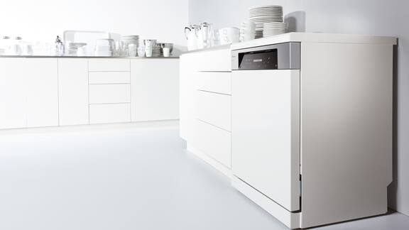 Bancada de cozinha branca com máquina de lavar louça branca encastrada, onde há louça na bancada.