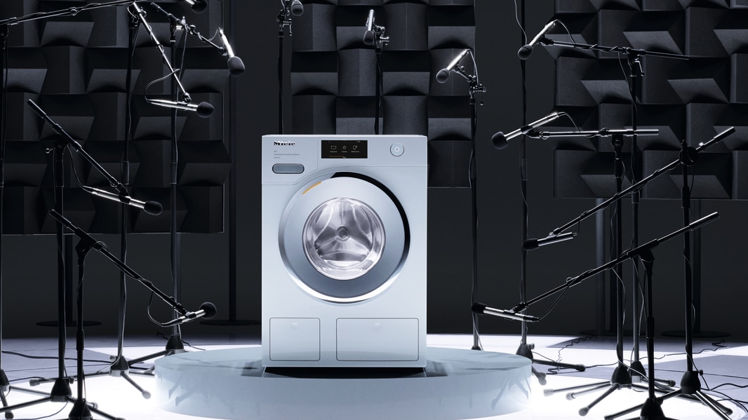 A Miele washing machine surrouned by splashes of water