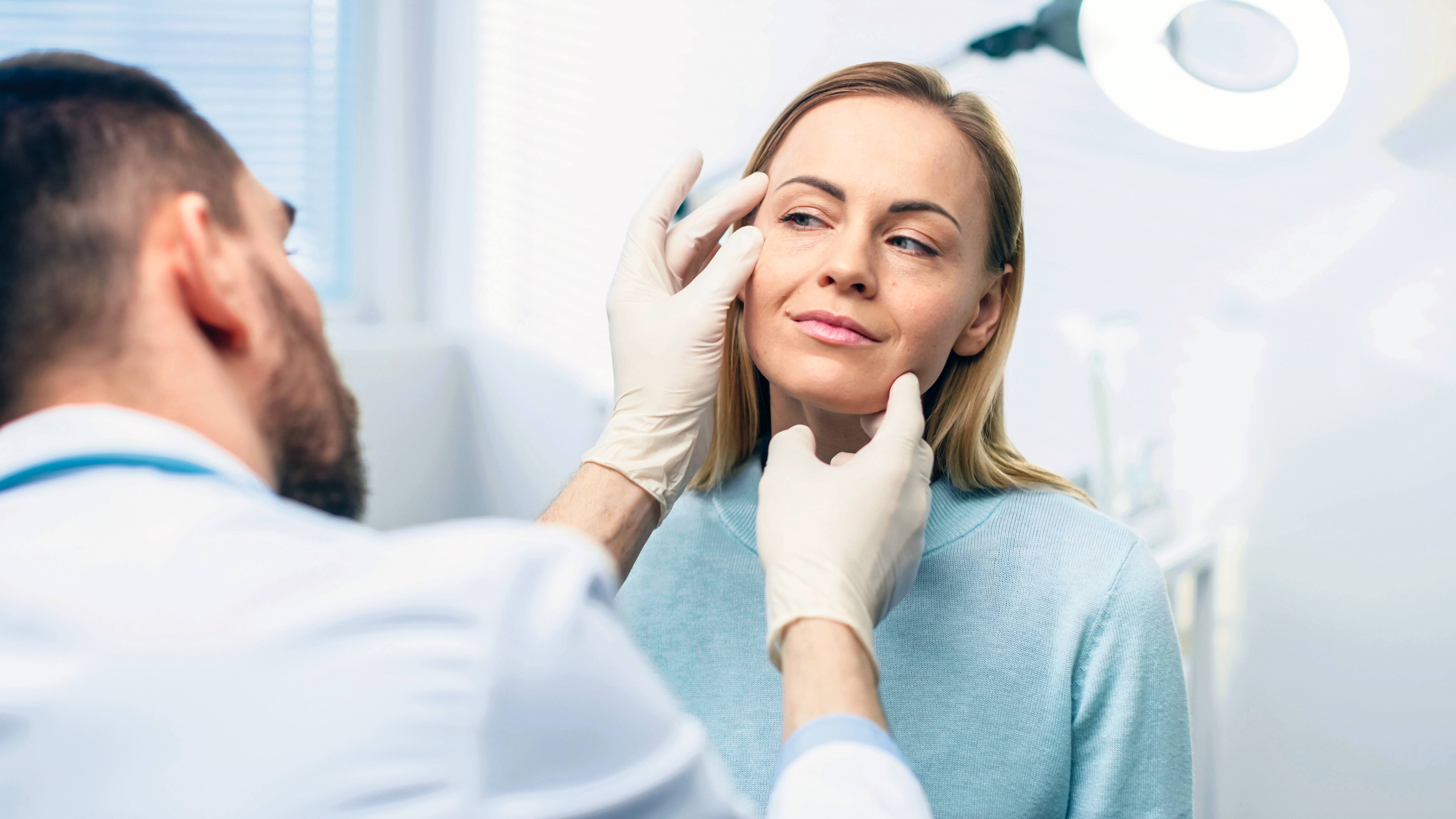 The skin on a woman's eye is examined by a dermatologist.