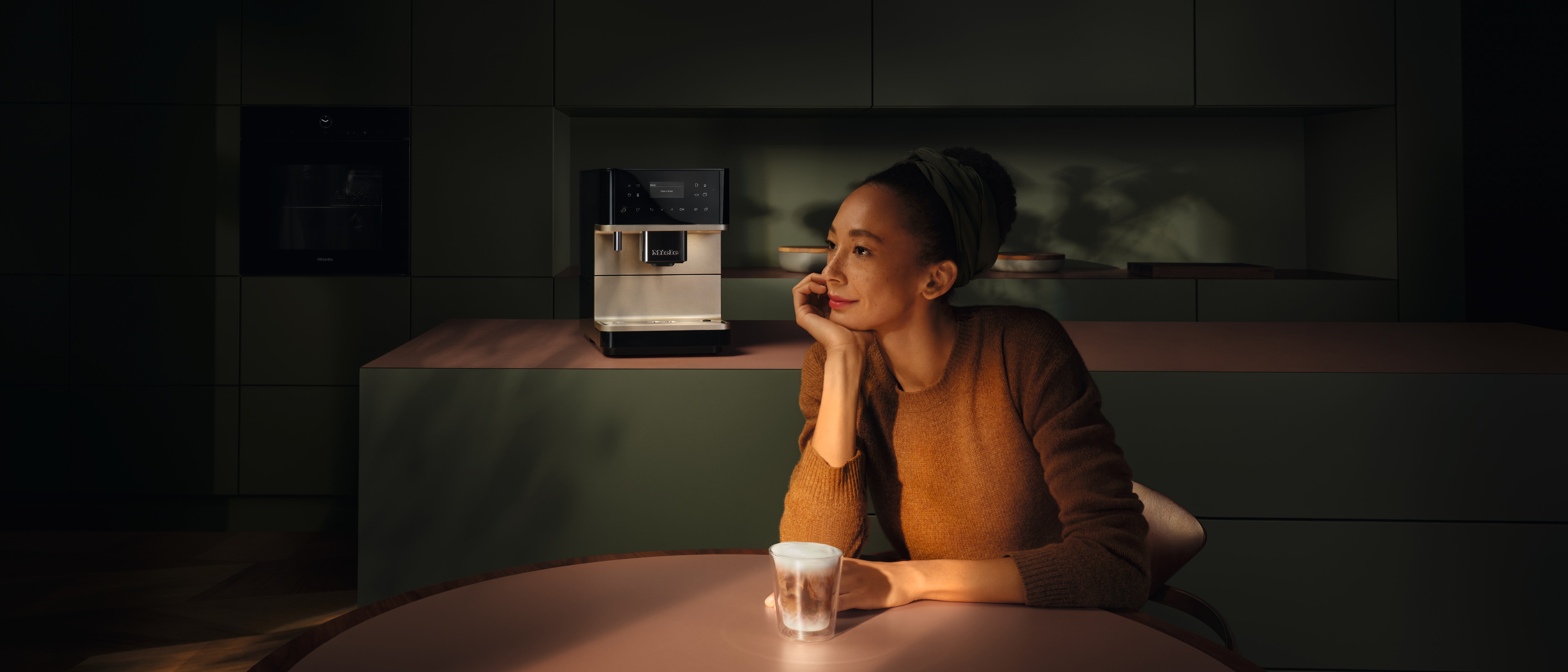 A woman enjoying a cup of coffee prepared with a Miele coffee machine