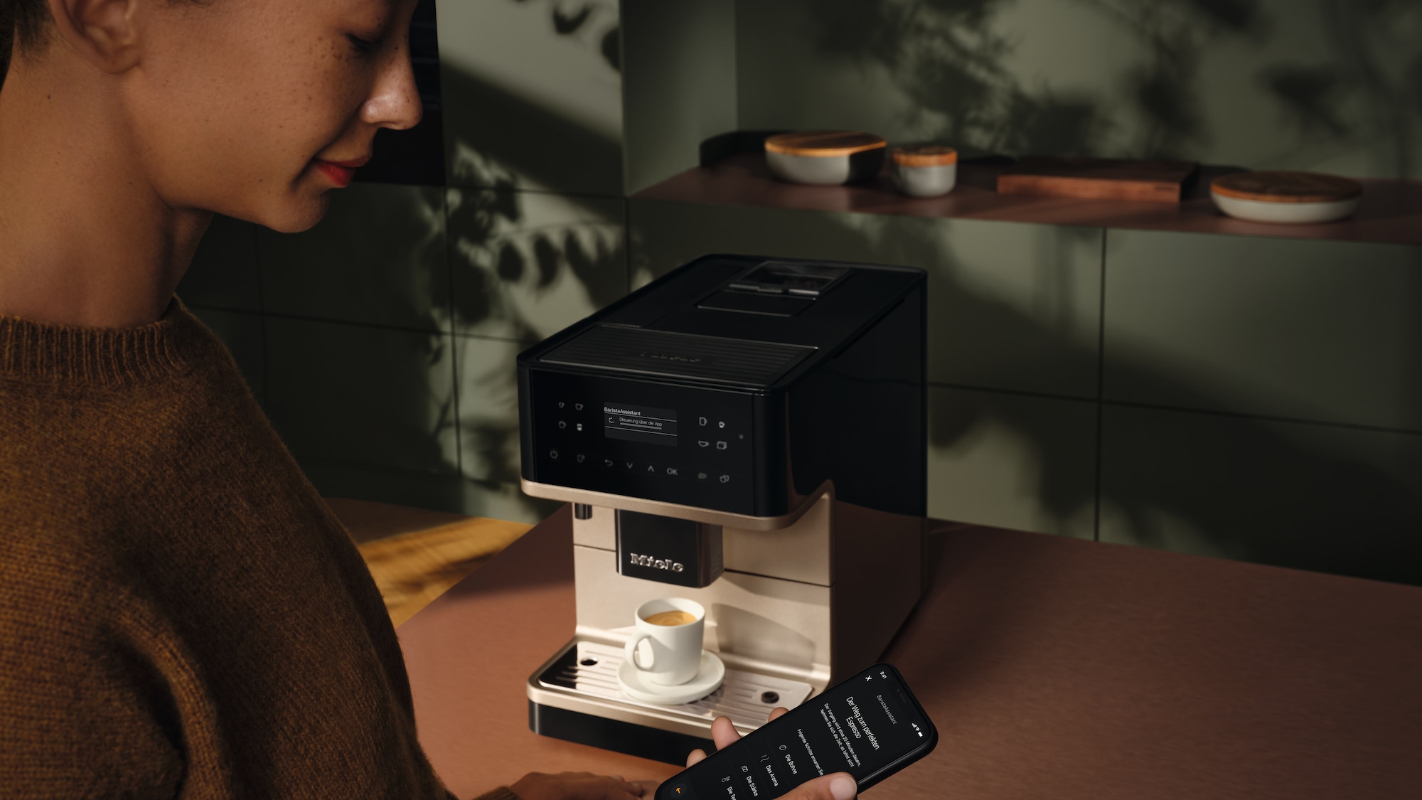 A person using her mobile phone to control the Miele coffee machine