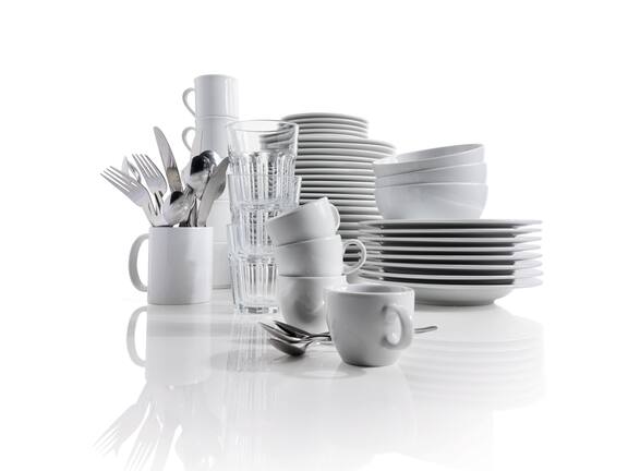 Stack of cleaned crockery consisting of plates, cups, glass and cutlery 