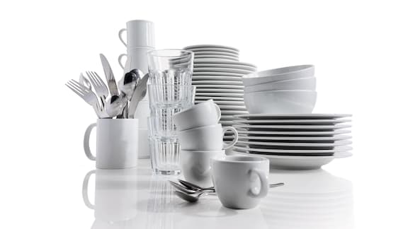 Stack of cleaned crockery consisting of plates, cups, glass and cutlery 