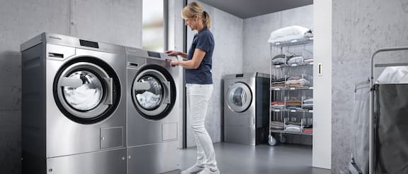 Cuidadora opera o comando da máquina de lavar roupa Benchmark.