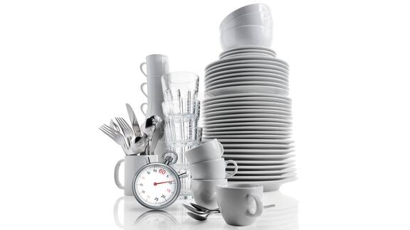 White dishes, cups and cutlery stacked next to a stopwatch