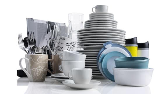 Colourful and white dishes, cups and glasses stacked next to each other and on top of each other