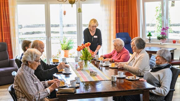 Mehrere Senioren sitzen gemeinsam an einem Tisch.