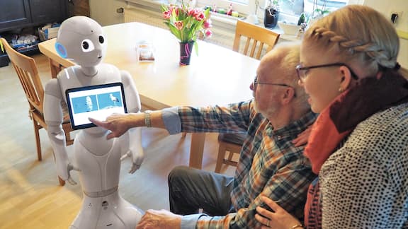 Ein älterer Herr tippt auf dem Bildschirm eines Roboters.