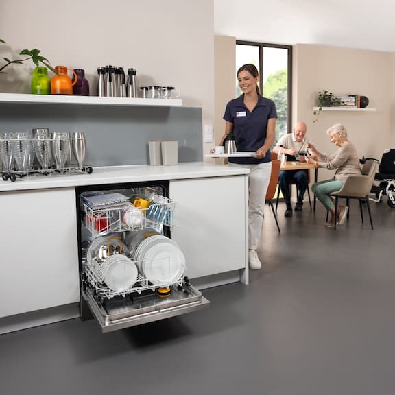 Lave-vaisselle Miele Professional MasterLine, ouvert et rempli de vaisselle dans les résidences pour seniors et maisons de retraite