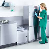Zdravotní sestra tiskne tlačítko nabídky na nerezovém mycím a dezinfekčním automatu podložních mís v přípravní lince.