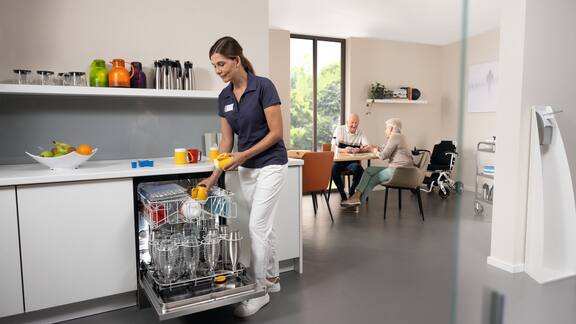 Egy gondozó betölti a Masterline mosogatógépet az idősek otthonának konyhájában.