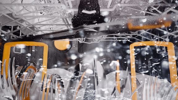 Bild eines sich bewegenden Sprüharms in einer Spülmaschine mit Besteck im Besteckkorb. 