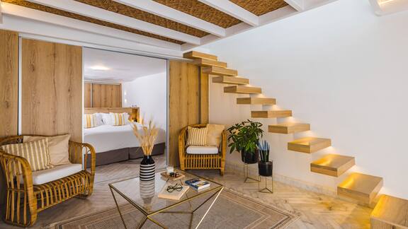 Een hotelkamer met een houten trap in de kamer en een zithoek. 
