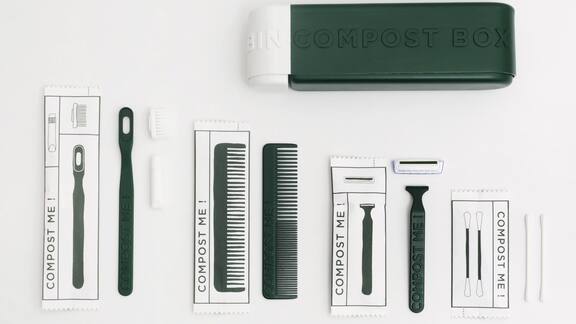 Des accessoires de soins verts, comme une brosse à dents, un peigne et un rasoir, posés côte à côte sur un fond blanc.