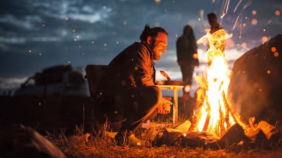 Un homme est assis près d‘un feu de camp 