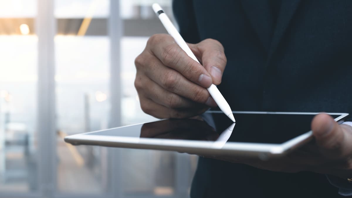 Jemand hält ein Tablet und tippt mit einen Tablet-Stift darauf.