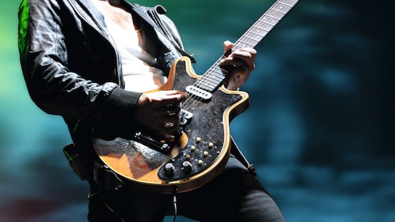 A person wearing a leather jacket and holding a guitar.  