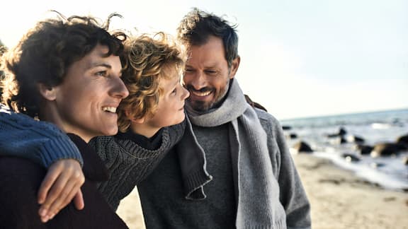 A small family of two parents and a child is on the beach 