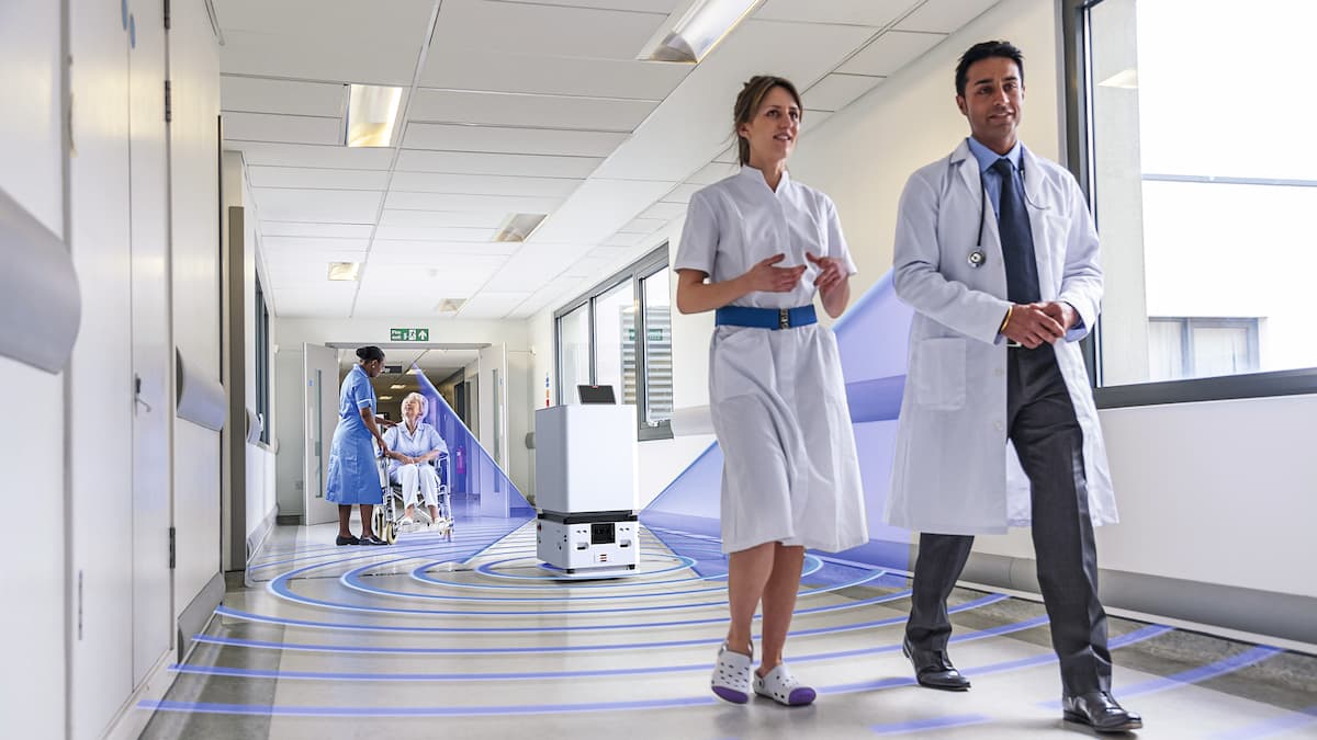 The Cliniserve robot drives across a corridor with people. It uses sensors to find its way. 