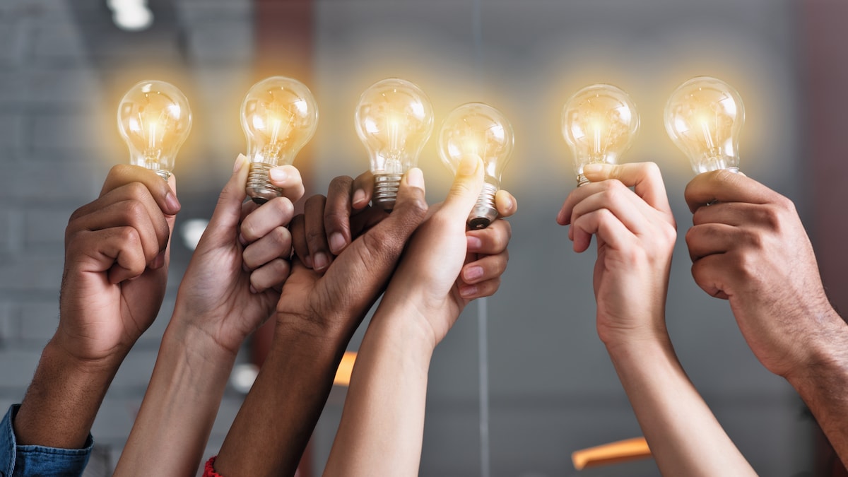 hands holding lighted light bulbs