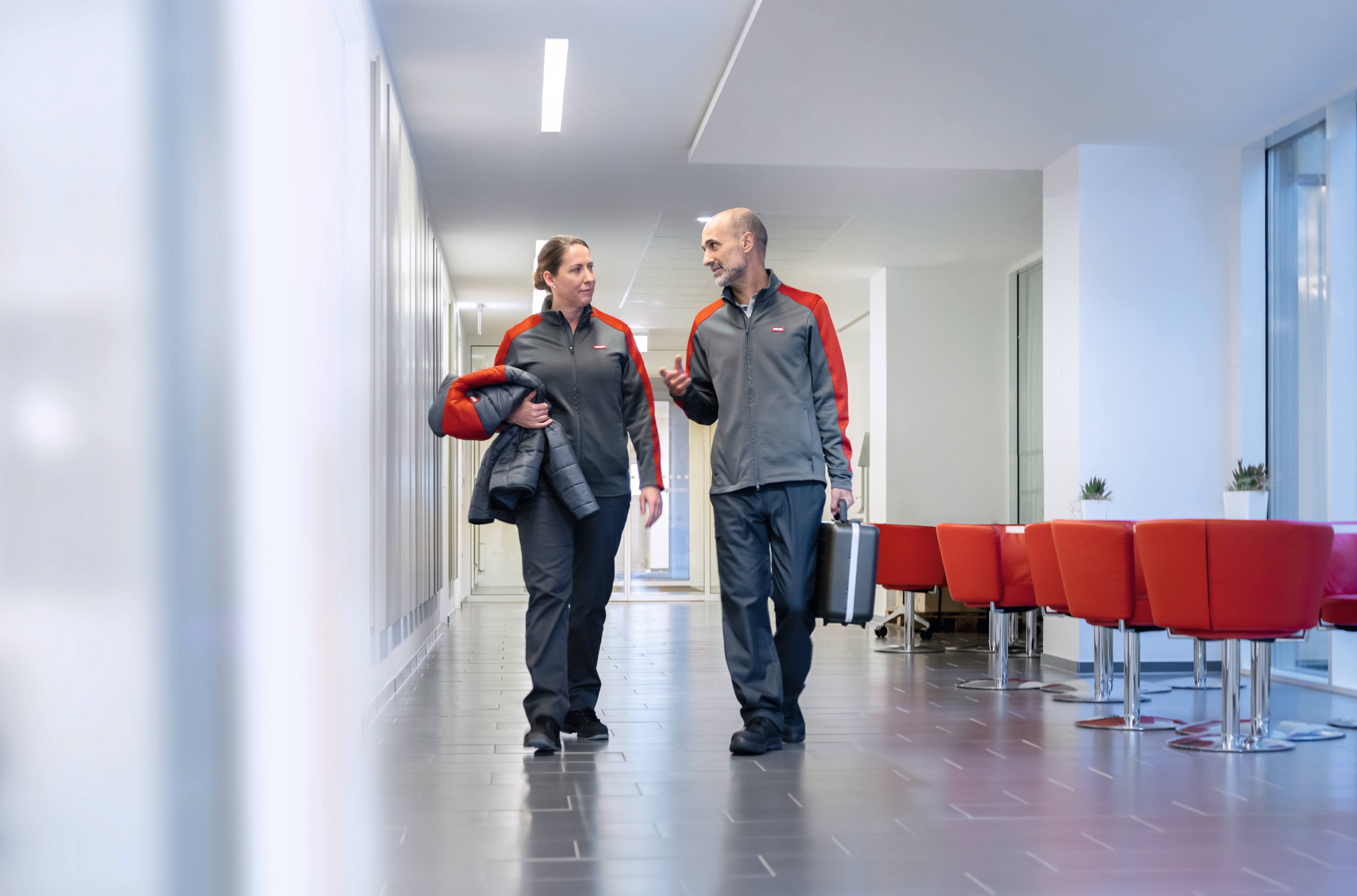 Muž a žena pracující pro Miele servis jdou po chodbě