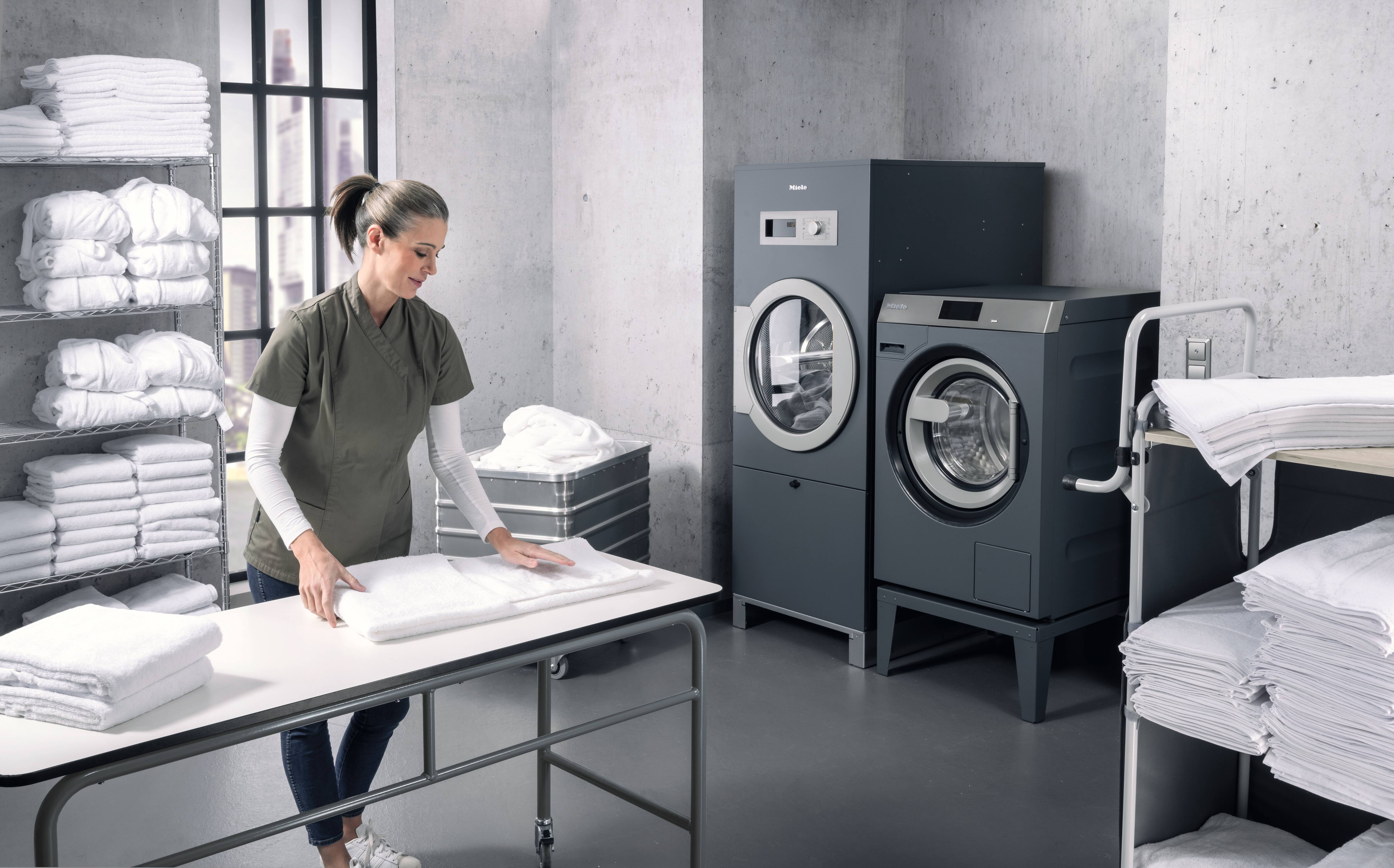 A woman in a laundry with Miele machines folding laundry
