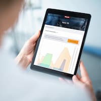 Shoulder view of a person holding a tablet. Various graphs for process documentation can be seen on the tablet screen.
