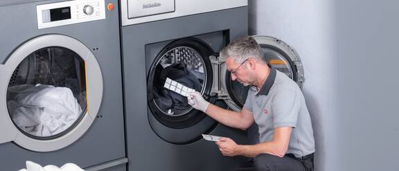 Servis teknisyeni çamaşır makinesinin kazanına bir ProHygiene test şeridi yerleştiriyor