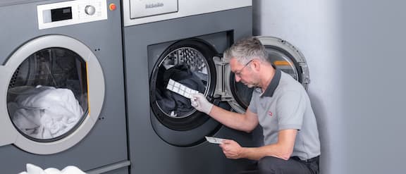Servicetechniker gibt einen ProHygiene Teststreifen in die Waschtrommel einer Waschmaschine