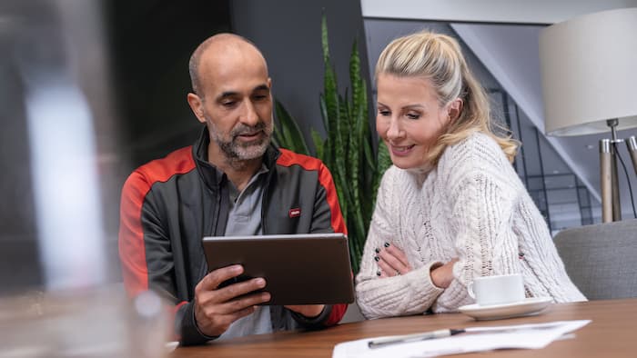 Servicetekniker i konsultation med en kunde, begge kigger på en tablet