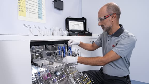 Technik Miele Professional sprawdza stomatologiczny termodezynfektor załadowany narzędziami stomatologicznymi