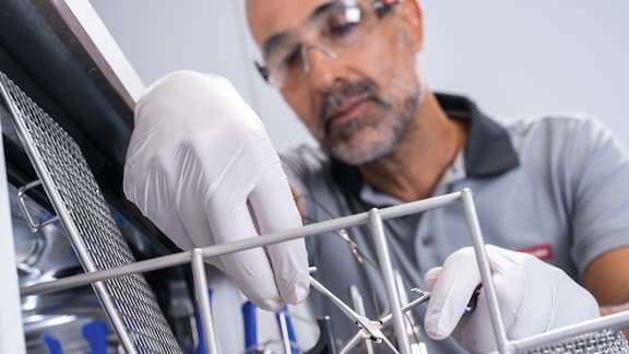 Een technicus draagt een veiligheidsbril en onderzoekt een testvoorwerp