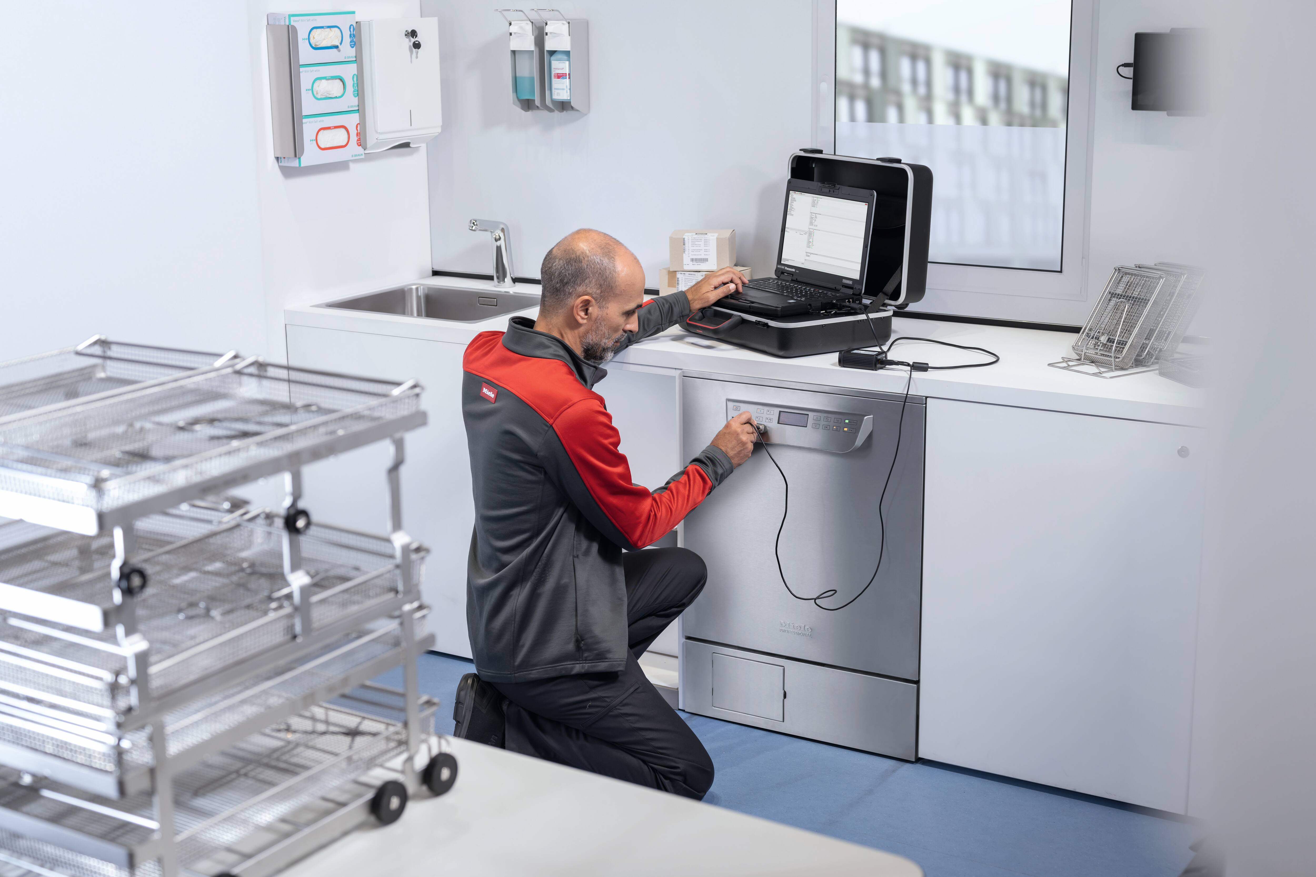 Un technicien de service conversant avec l’assistante médicale devant un stérilisateur compact.