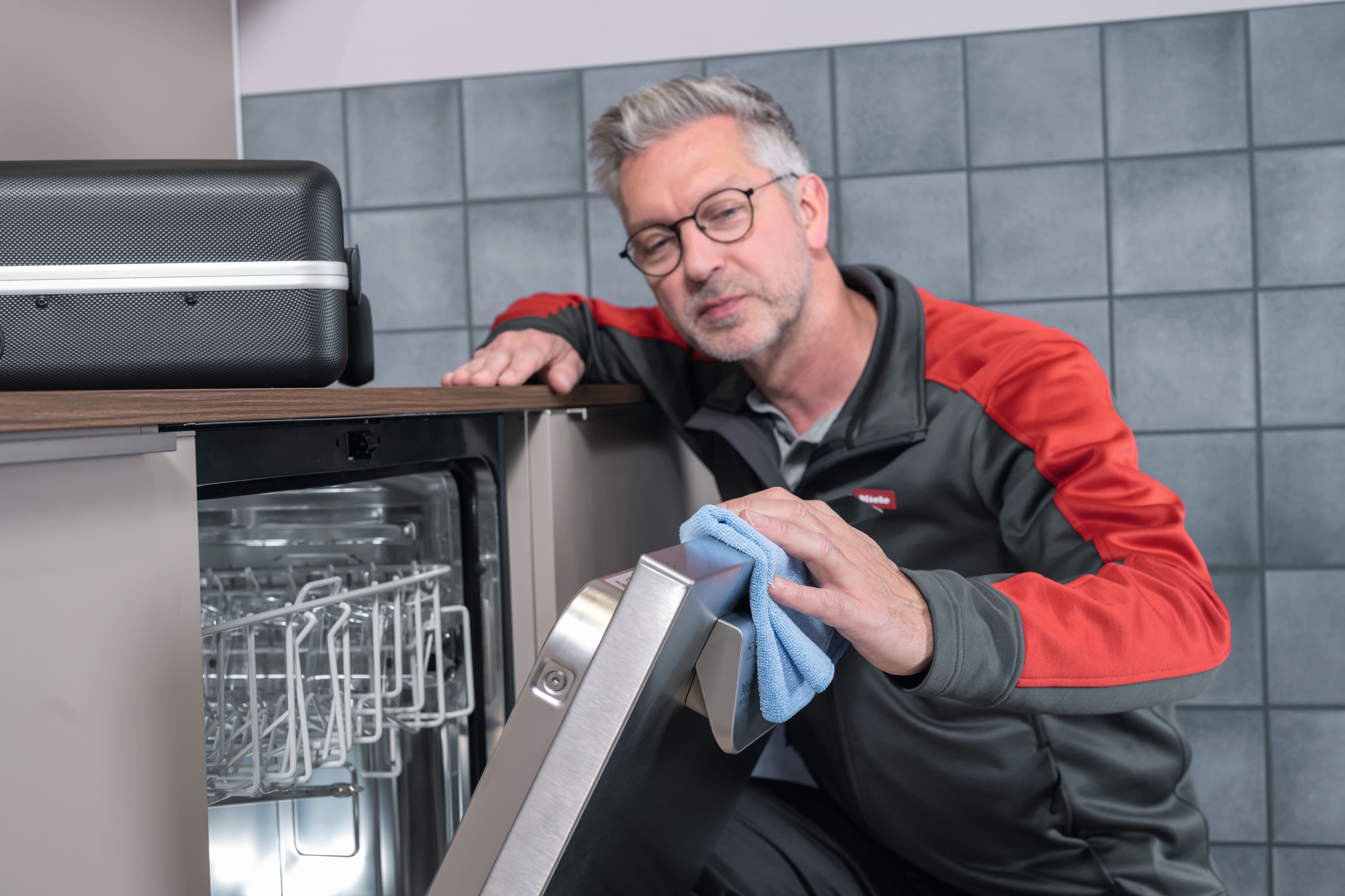 Tecnico Miele che pulisce e fa manutenzione a una lavastoviglie