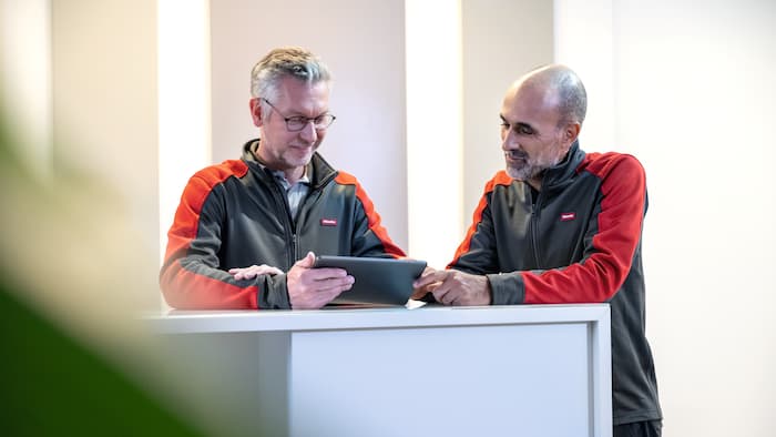 Zwei Servicetechniker schauen auf ein Laptop.