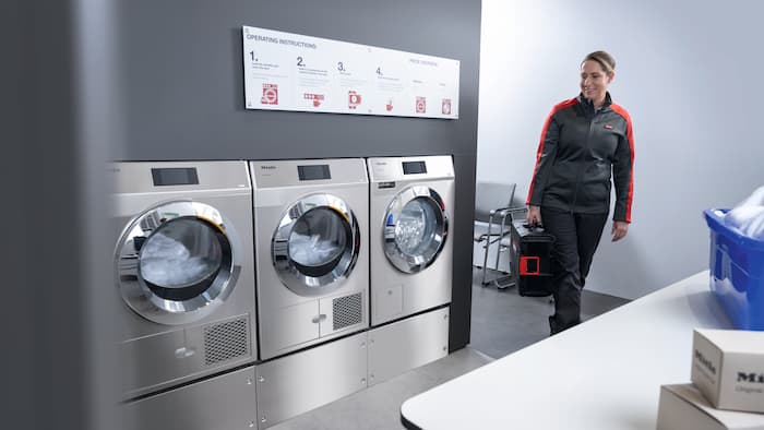 Miele service technician approaching washing machines with a toolbox