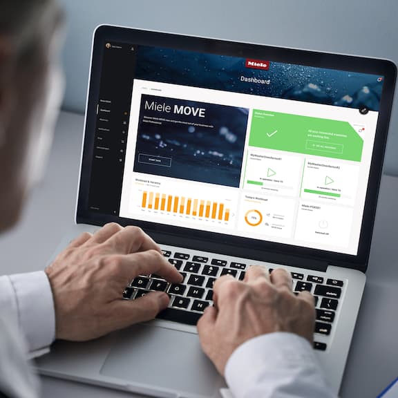 An employee sitting at a laptop where the Miele MOVE Connect dashboard can be seen.