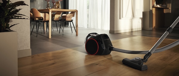 bagless canister vacuum on a hardwood floor in a house