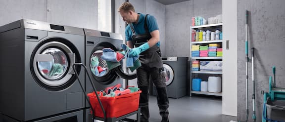 Bild aus einer Wäscherei, in der ein Mann eine Miele-Waschmaschine belädt.