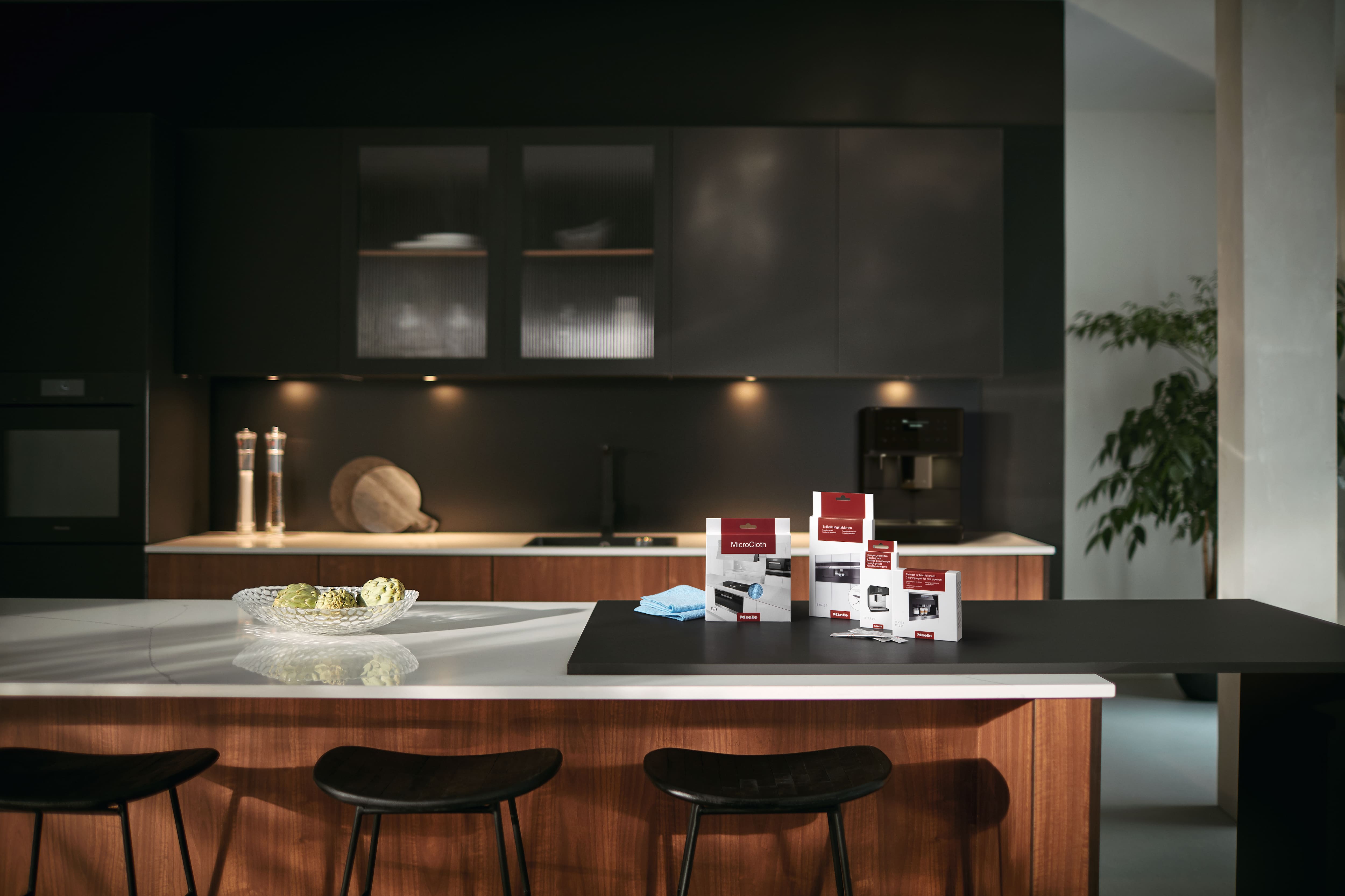 descaling tablets, milk pipework cleaner, cleaning tablets, and a microfiber cloth displayed on a kitchen countertop