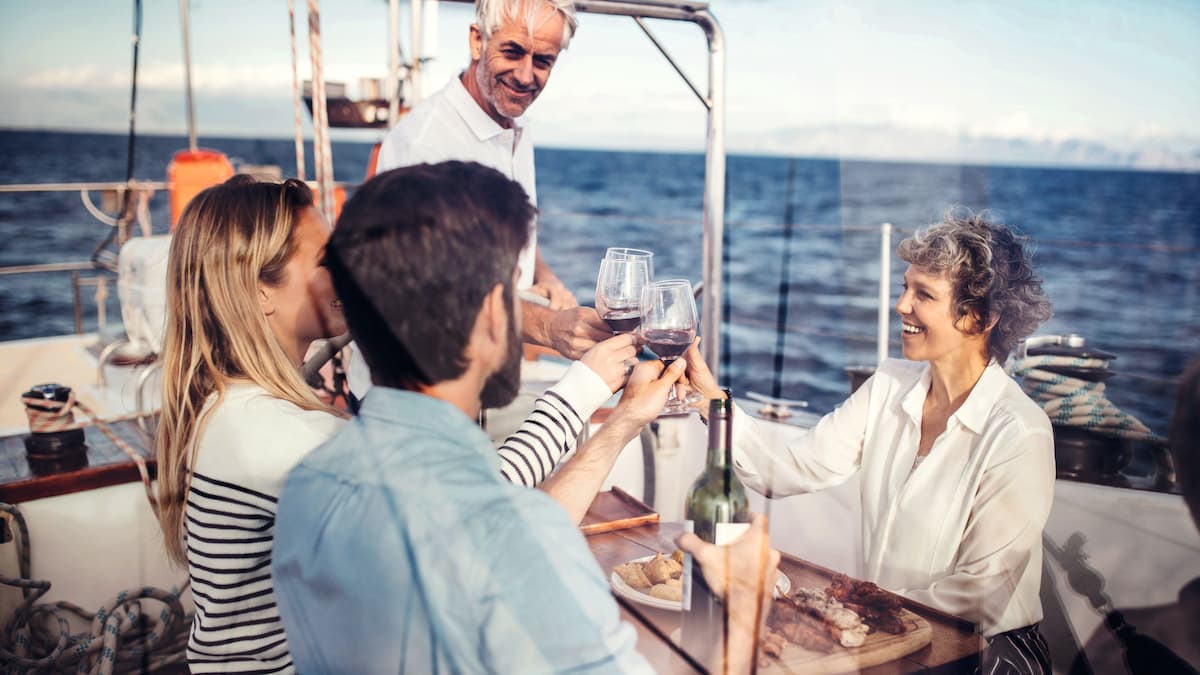 Drei Personen teilen sich den Wein auf einer Yacht