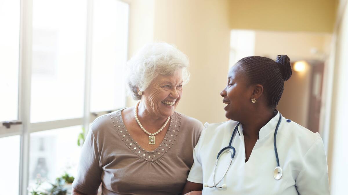 Un'infermiera cammina con una signora anziana in una casa di riposo