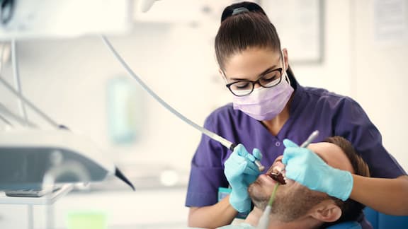 Stomatolog wykonuje zabieg na pacjencie leżącym na fotelu dentystycznym