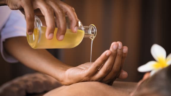 Représentation imagée d’une personne laissant s’écouler de l’huile de massage dans la main